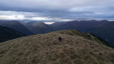 Drone-shot-of-a-woman-walking-with-her-dog-on-a-mountain-range
