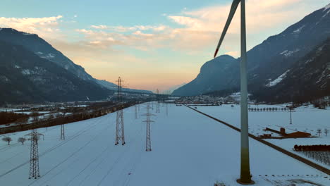 Long-powerlines-next-to-a-modern-rotating-windmill-in-the-Rhone-Valley-on-a-winter-evening