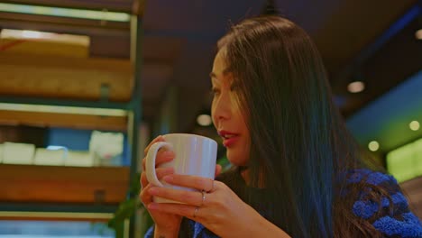 beautiful-Asian-oriental-female-girl-woman-model-in-cafe-restraurant-with-a-cup-of-beverage-drinking-talks,-chats,-smiles,-fun-and-dialogue,-conversation