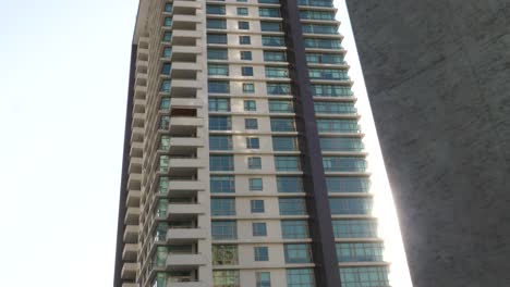 Slow-Dolly-Left-Reveal-Past-Concrete-Wall-Looking-Up-At-Emaar-Residential-Apartments-Located-In-Crescent-Bay,-Karachi