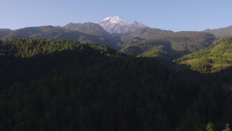 Aerial-footage-of-the-forest-sorrounding-the-volcano,-the-mountain-in-the-background