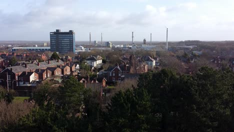 Luftaufnahme-über-Parkbäume-Zum-Industriellen-Stadtbild-Gehäuse-Mit-Pilkingtons-Blue-Skyscraper,-Merseyside,-England