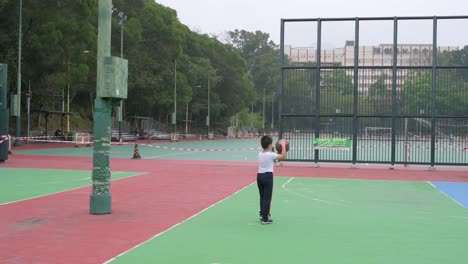 A-child-wearing-a-face-mask-while-holding-a-basketball-ball-walks-at-an-empty-colorful-basketball-court-closed-due-to-Covid-19-Coronavirus-outbreak-and-restrictions