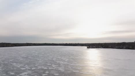Frozen-Canadina-lake-Wilcox-near-Toronto-in-the-early-spring,-Drone-descending