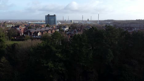 Luftbild-über-Parkbäume-Zum-Industriellen-Stadtbild-Mit-Blauem-Wolkenkratzer-Auf-Der-Skyline,-Merseyside,-England