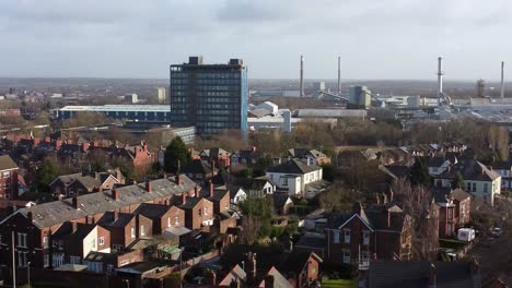 Aerial-view-over-park-trees-to-industrial-townscape-property-with-blue-Pilkingtons-skyscraper,-Merseyside,-England