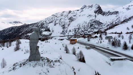 Eagle-sculpture-of-stone-overlooking-the-Simplon-pass-to-the-pass-hospice-with-in-the-background-the-high-Swiss-alps-covered-by-snow
