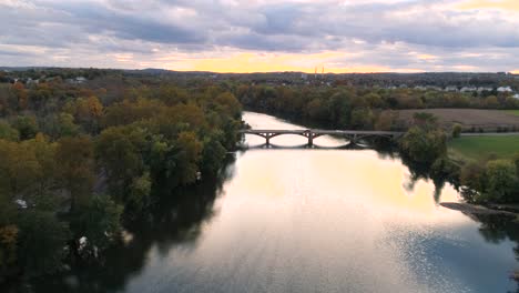 Phoenixville-Schuylkill-River-4k-Drone-in-Golden-Hour-during-Fall-Autumn-flying-over-river-into-sunlight