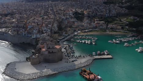 Aerial-View-Of-Castello-Arabo-Normanno-Located-Beside-Castellammare-Del-Golfo-Port-With-Town-View-In-Background