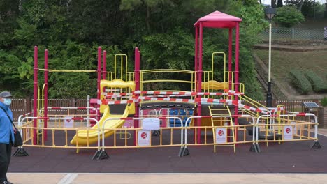 People-walk-past-a-closed-slide-play-with-tapes-and-barriers-seen-at-a-public-playground-due-to-the-Covid-19-Coronavirus-outbreak-and-restrictions-in-Hong-Kong