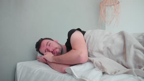 Sleeping-man,-caucasian-white-with-beard,-wakes-up-in-the-morning,-tired-stretch,-open-eyes,-relaxed-get-up-in-bedroom-indoor-home