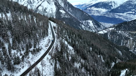 Camión-Conduciendo-Por-La-Larga-Carretera-Asfaltada-Negra-Con-Impresionantes-Vistas-De-Las-Altas-Montañas-Suizas