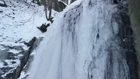 Drone-flying-near-an-icy-waterfall-in-a-forrest-in-Switzerland