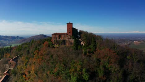 Aerial-Ascending-Shot-Over-Trees-On-Hilltop-To-Reveal-Castle-of-Montalto-Pavese-In-Lombardy,-Italy