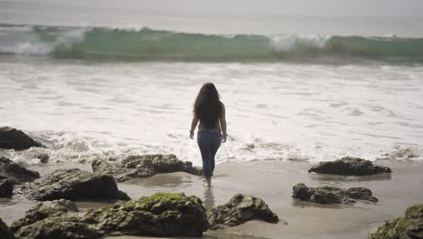 Girl-walking-through-water-and-sand-on-El-Matador-Beach-in-Southern-California-near-Malibu---wide-shot