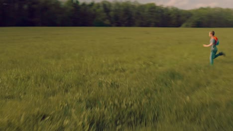 Young-boy-child-running-fast-over-meadow-with-backpack