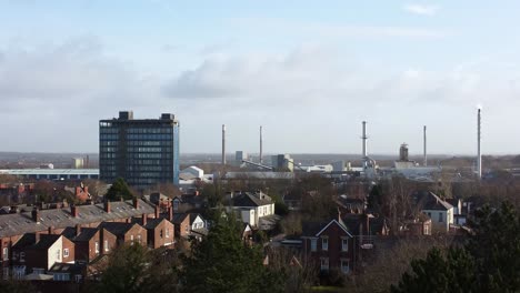 Absteigender-Luftblick-über-Parkbäume-Zum-Industriestadtbild-Mit-Blauem-Wolkenkratzer,-Merseyside,-England