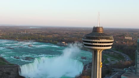 Niagara-falls-from-Canada-side-with-observation-tower-during-sunset,-Drone-descending,-close-up