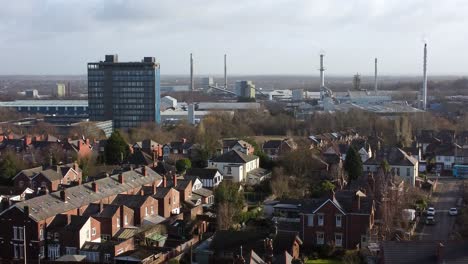 Aerial-view-over-park-trees-to-suburban-industrial-townscape-with-blue-Pilkingtons-skyscraper,-Merseyside,-England