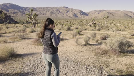Girl-Photographing-Joshua-Tree-National-Park-desert-California-with-a-Sony-A1-camera---on-her-phone-wide-of-landscape