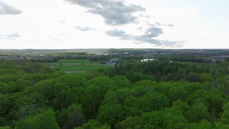 Golf-pitch-in-Aurora,-Ontario,-Canada-in-may,-panorama-on-the-city-from-a-drone,-Drone-flying-forward-above-trees