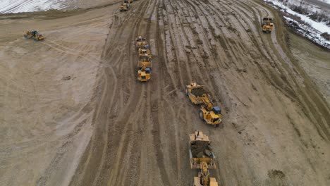 Wheel-tractor-scrappers-work-in-a-construction-site-to-level-out-and-grade-an-area-for-a-new-housing-development-as-seen-from-an-aerial-drone-vantage-point