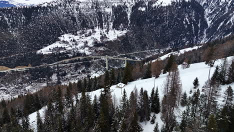 Weite-Drohnenaufnahme-Der-Hochmodernen-Ganterbrücke-Zwischen-Den-Mit-Weißem-Schnee-Bedeckten-Schweizer-Hochalpen
