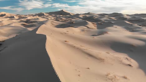 Aerial-drone-shot-flying-over-crest-of-a-sand-dune-with-footsteps-in-Mexican-desert
