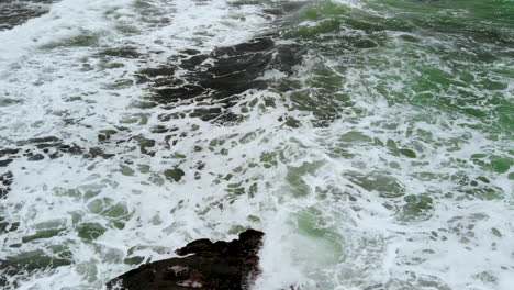 Dark-green-and-wild-sea-waves-splashing-at-a-rocky-beach-near-an-exotic-Indonesian-island