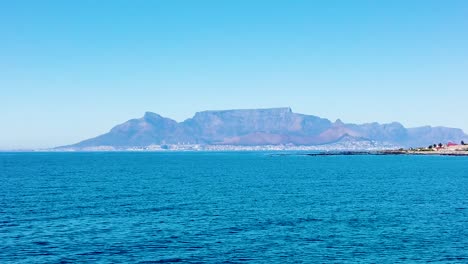 Salida-De-Robben-Island-En-Barco-Hacia-Ciudad-Del-Cabo,-Con-La-Montaña-De-La-Mesa-Al-Fondo