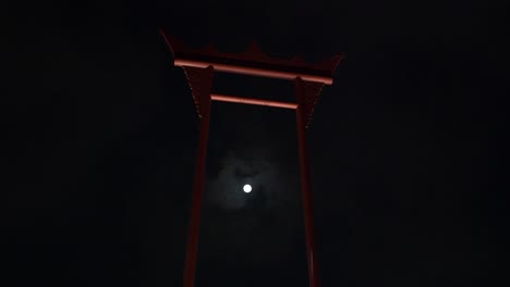 A-4K-video-clip-of-a-super-moon-passing-behind-the-Giant-Swing,-Bangkok,-Thailand