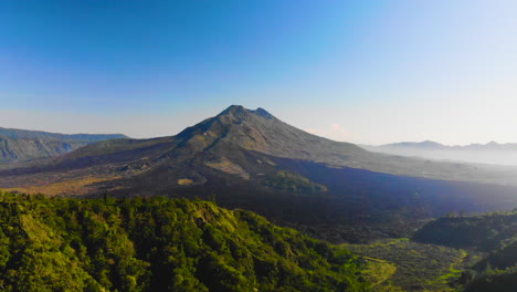Drone-flying-over-trees-to-visualize-Mount-Batur-,-an-active-vulcano-in-Bali,-Indonesia