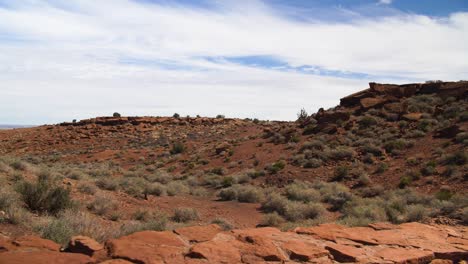A-wide-shot-of-the-arid,-desert-landscape-with-a-stone-wall-in-the-foreground-at-Wupatki-National-Monument-in-Arizona