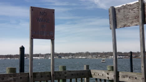 Pan-to-old,-weathered-No-Wake-in-Harbor-sign-on-pressure-treated-wood-deck