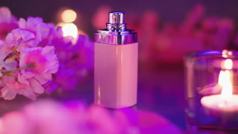 Pink-perfume-bottle-composition-with-flowers-and-candle-lights