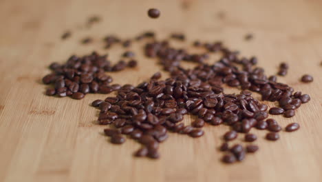 Coffee-Beans-Dropping-into-Pile-on-Wooden-Surface-in-Slow-Motion