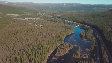 Crane-up-and-tilt-down-drone-shot-over-a-river-in-a-large-forest-in-mid-Norway