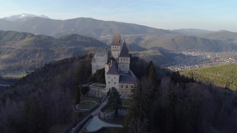 Rising-Drone-Shot-of-a-Castle-on-a-Hill-with-Mountains-in-the-Background,-4k-UHD