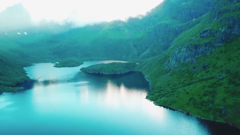 Panning,-crane-down-drone-shot-of-surrounding-rocky-hills-over-lake-Ågvatnet-in-Lofoten