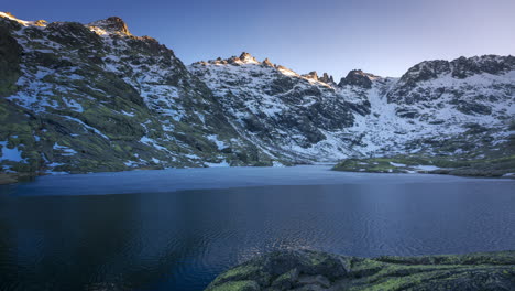 Sunset-at-Laguna-Grande-de-Gredos,-perfect-reflection-of-the-mountains-in-the-half-frozen-lake