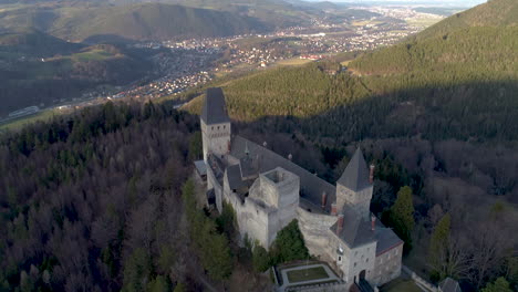 Drone-Shot-of-a-Castle-on-a-Mountain-revealing-a-beautiful-Landscape,-flying-backward-while-tilting-up,-4k-UHD