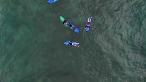 Close-top-down-aerial-video-of-surfers-paddling-and-surfing