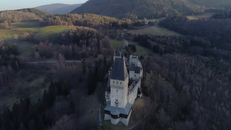 Umlaufende-Drohnenaufnahme-Einer-Burg-Auf-Einem-Berg-Bei-Sonnenuntergang-In-Österreich,-4k-Uhd