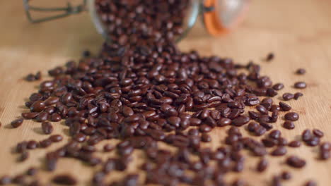 Kaffeebohnen-Werden-In-Zeitlupe-Aus-Dem-Einmachglas-Auf-Die-Holzoberfläche-Verschüttet