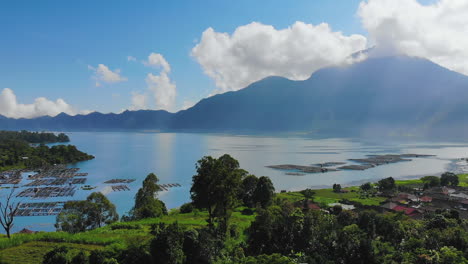 Danau-Batur-lake-and-active-volcano-Gunung-Batur,-with-sun-rays-shining-through-the-clouds