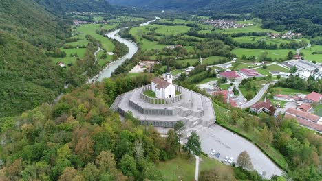 Aerial-drone-shot-of-orbiting-around-a-church-in-Slovenia-with-mountains-in-the-background,-4k-UHD