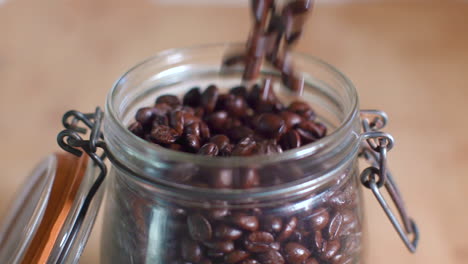 Close-Up-of-Pouring-Coffee-Beans-into-Mason-Jar-with-Lid-in-Slow-Motion