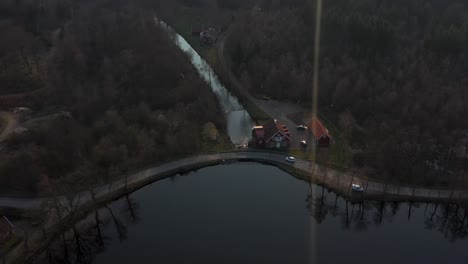Drone-footage-of-a-car-driving-beside-a-lake-in-Sweden,-VÃ¤stersjÃ¶n-outside-Ã„ngelholm-in-SkÃ¥ne