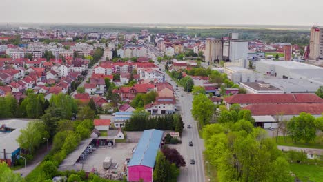 Flying-backward-with-drone-and-filming-hyperlapse-in-the-small-city-Brcko-district-in-Bosnia-and-Hezegovinia,-above-cars-and-trucks-and-railroad