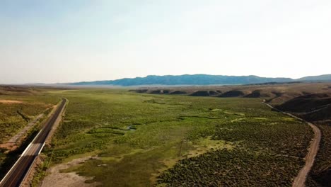 Desert-Highway-at-sunset-and-dusk-with-a-snake-river-and-plateaus-from-a-drone-in-1080p-summer-of-2018